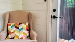 En beige lænestol med en farverig chevron-pude, et billede af fisk i ramme på væggen og en skydedør til udendørs.