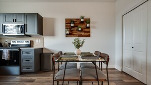 A modern kitchen with grey cabinets, a microwave, stove, and a dining area with a table and chairs.