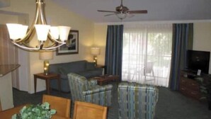 A hotel room with a dining area, a sofa, a television, and a ceiling fan. - Orlando Christmas Week! (Orlando)