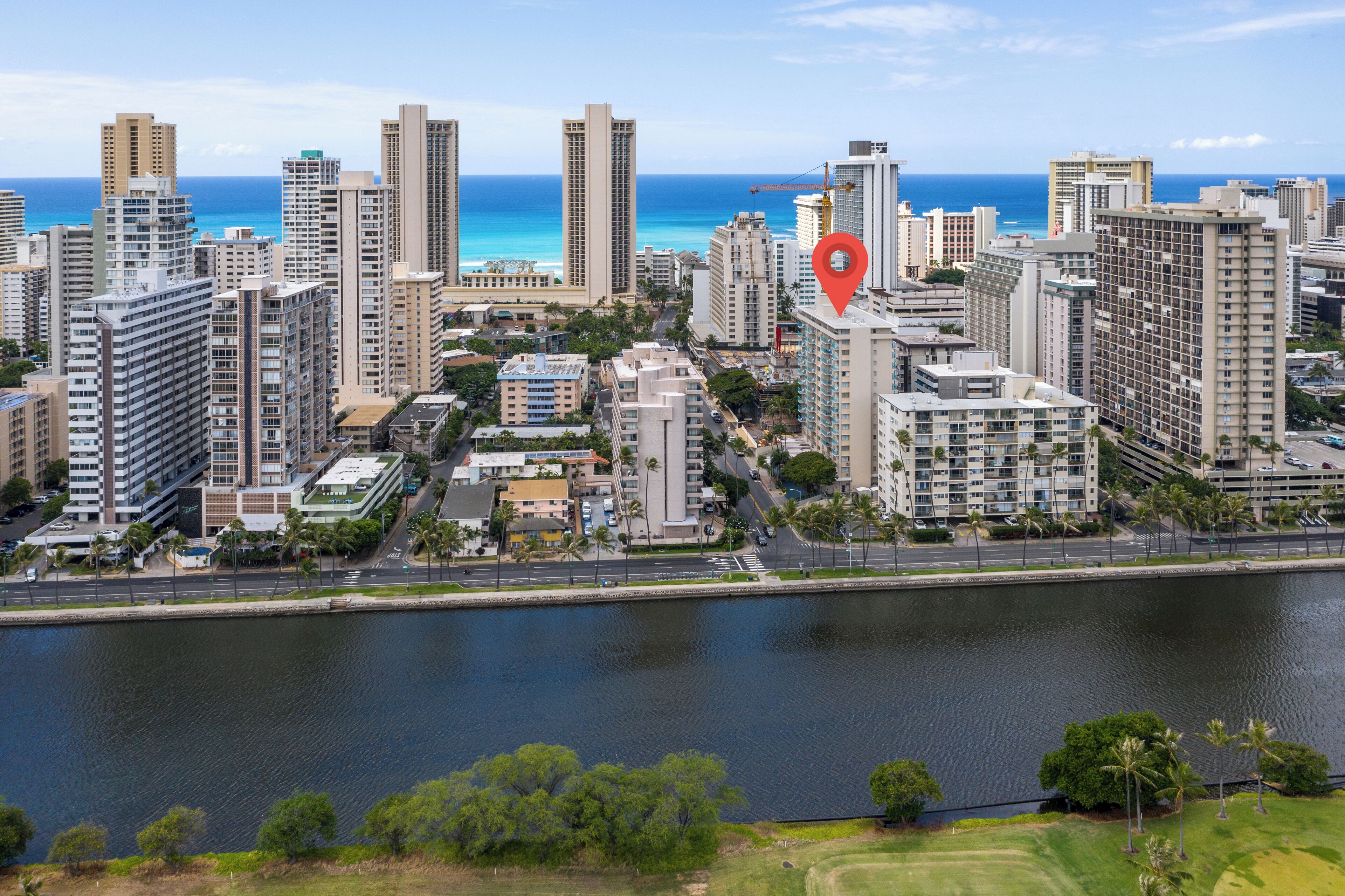 A high-rise hotel with a view of the ocean, surrounded by other buildings and a body of water.
