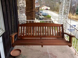 Situated on a porch, this bench offers a view of the surrounding neighborhood.