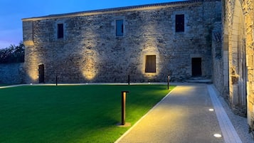 A stone building with a paved pathway and a well-maintained lawn.