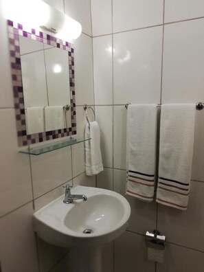 Chuveiro, toalhas de banho, sabonete, papel higiênico