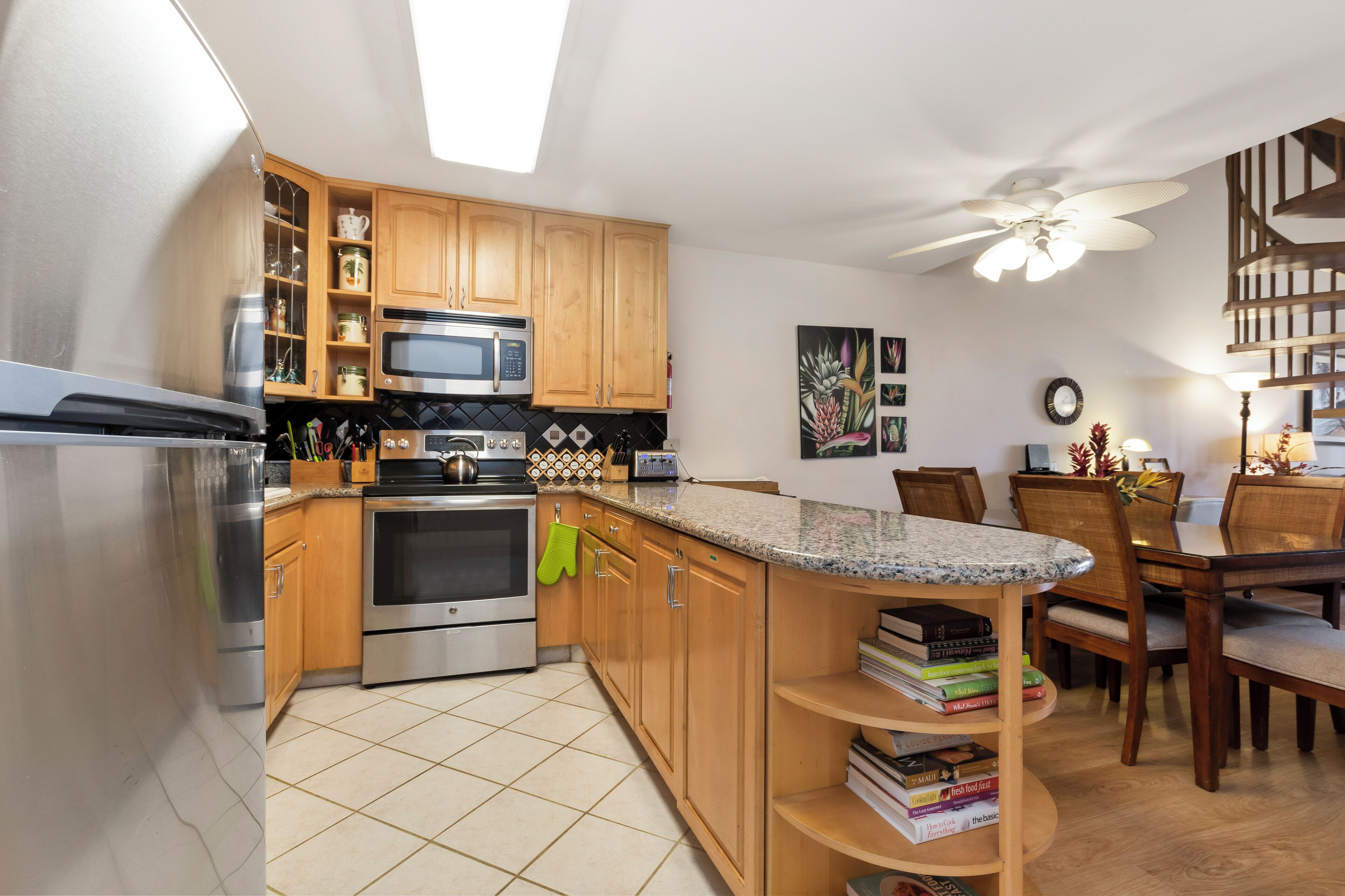 A modern kitchen with wooden cabinets, stainless steel appliances, and a granite countertop.