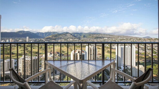 A balcony with a view of a cityscape, including high-rise buildings and a green park. - Aston Waikiki Sunset 1BMV | Mountain Views – Heated Pool & Spa (Honolulu)