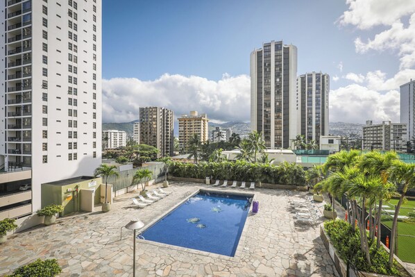A rooftop pool with two turtles, surrounded by high-rise buildings and lush greenery. - Aston Waikiki Sunset 1BST | City Views – Heated Pool & Spa (Honolulu)
