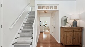 A staircase with striped carpet leading to a landing with a decorative ceiling.