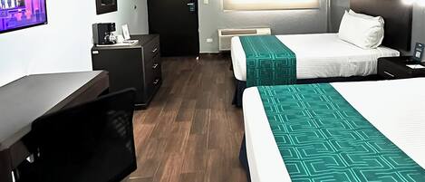 Une chambre d’hôtel avec deux lits, un bureau, une chaise, une télévision et une fenêtre avec des stores.