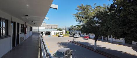 A building with a covered walkway and a parking area with cars.