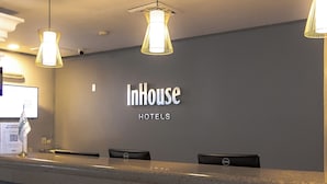 Un comptoir d’accueil d’hôtel avec une enseigne indiquant « InHouse HOTELS » et deux écrans d’ordinateur.