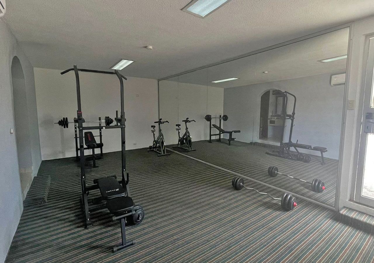 A gym with exercise equipment, a mirror, and a striped floor.