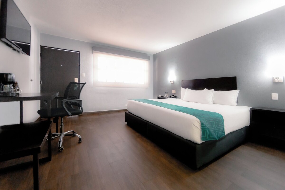 A hotel room with a bed, a desk, and a chair.