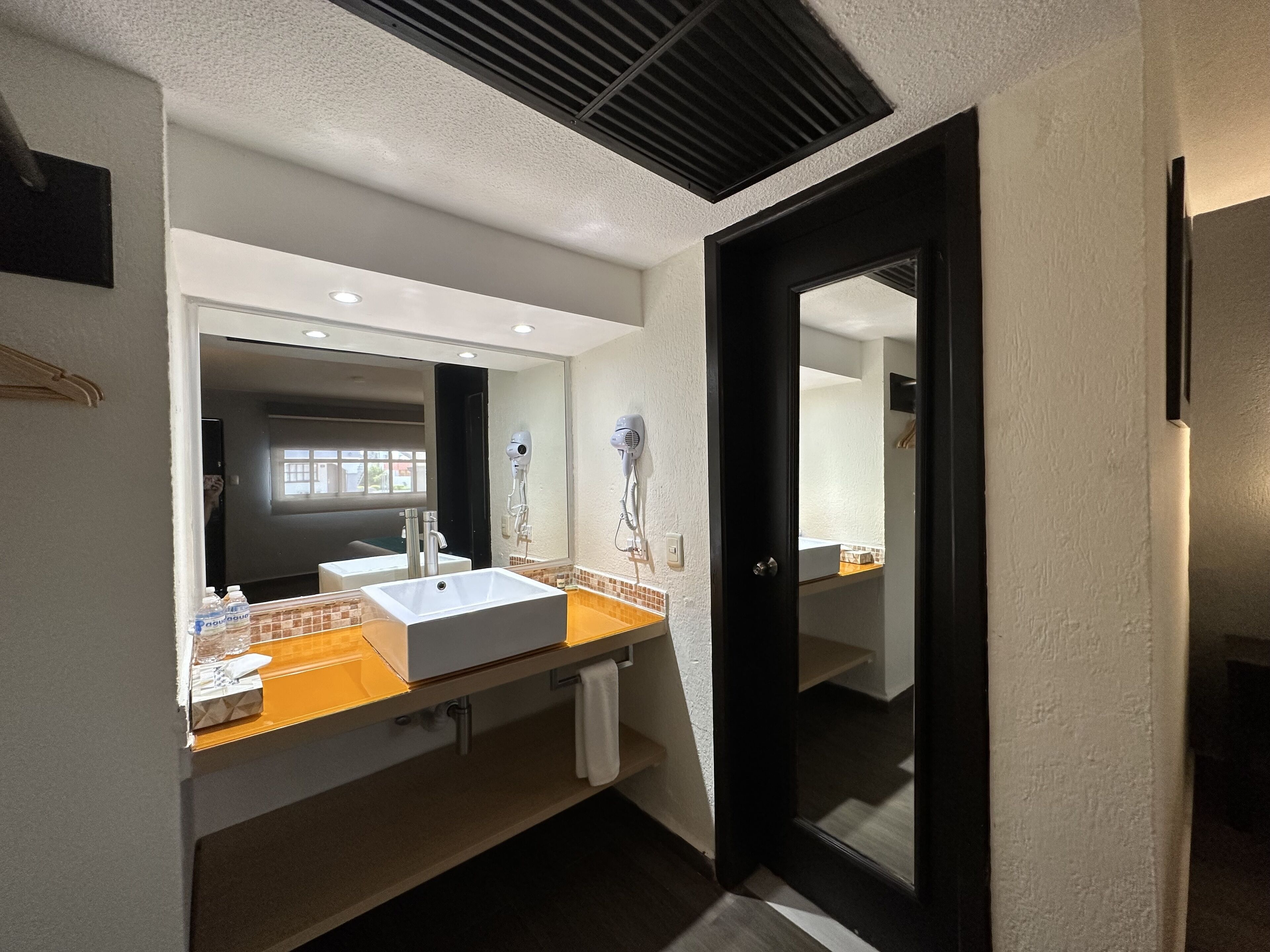Un baño moderno con un lavabo blanco, un espejo y una puerta negra.