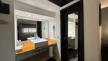 Un baño moderno con un lavabo blanco, un espejo y una puerta negra.