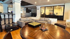 Un vaste espace de détente avec une table ronde en bois, des sièges confortables et un jeu d’échecs.