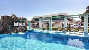 A swimming pool with lounge chairs and a stone wall.