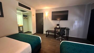 A hotel room with two beds, a desk with a chair, a TV, and a wardrobe.