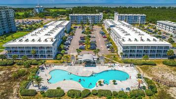 Un resort con varias construcciones, un área de piscina central y vista al océano.