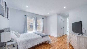 Une chambre à coucher moderne avec un lit, une table de chevet et un téléviseur.