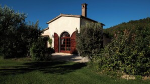 A building with a red door and arched windows, surrounded by greenery. - 3 bedroom private vacation home in tuscany (Toscana)