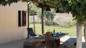 An outdoor wooden table with benches, a chair, and various items like a basket, wine glasses, and bottles. - 3 bedroom private vacation home in tuscany (Toscana)