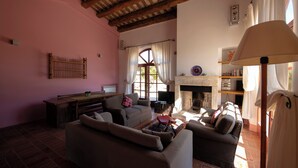 A cozy living room with a fireplace, a sofa, a coffee table, and a television. - 3 bedroom private vacation home in tuscany (Toscana)