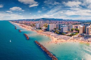 Un paysage urbain côtier avec une plage, des bâtiments et un ciel dégagé.