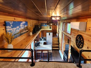 Cozy cabin-style interior with a kitchen area, wooden paneling, and a large window.