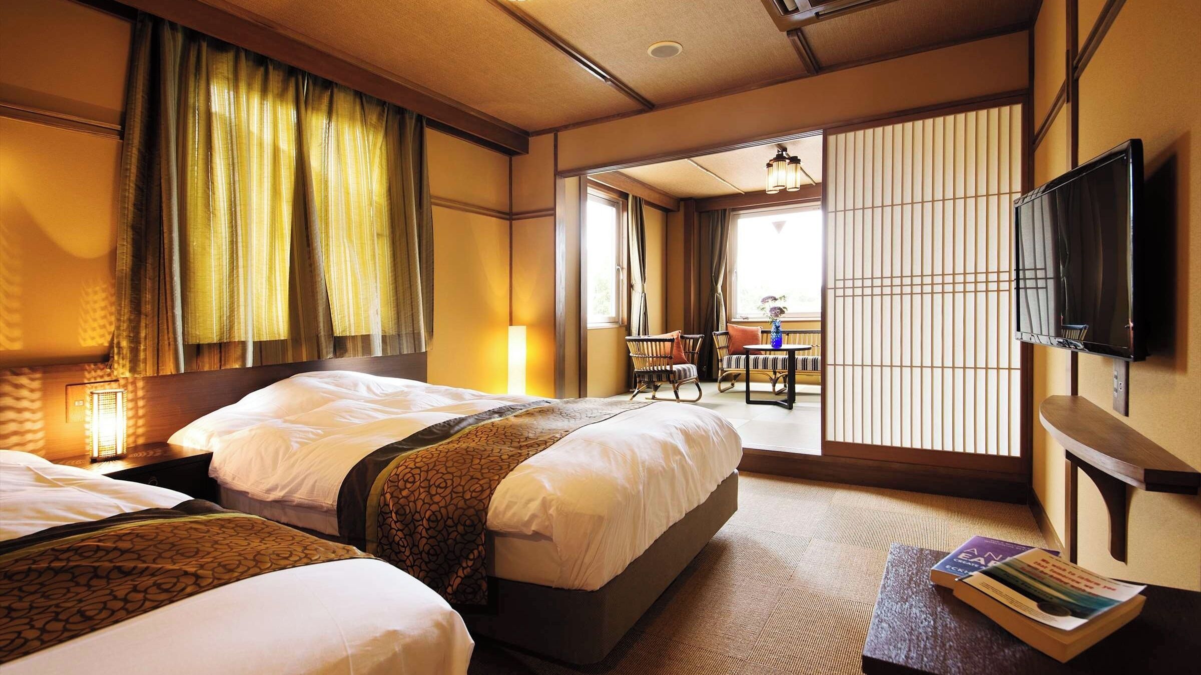 A hotel room with two beds, a TV, a bookshelf, and a view of the outside.