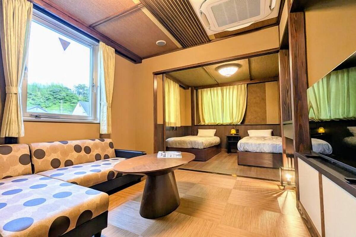 A compact room with a sofa, a table, and two beds.