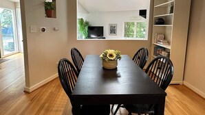 A dining area with a dark wooden table, six black chairs, and a sunflower centerpiece. There is a ceiling light above the table, and a small potted plant on the wall. - Duke-Rockwood Gem: 2BR/2BA w/ Office & Fenced Yard (Durham)