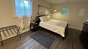 A bedroom with a bed, bedside table, lamp, and a window with curtains. - Duke-Rockwood Gem: 2BR/2BA w/ Office & Fenced Yard (Durham)