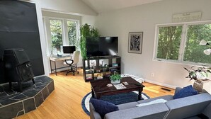A modern living room with a fireplace, a television, a sofa, and a coffee table. - Duke-Rockwood Gem: 2BR/2BA w/ Office & Fenced Yard (Durham)