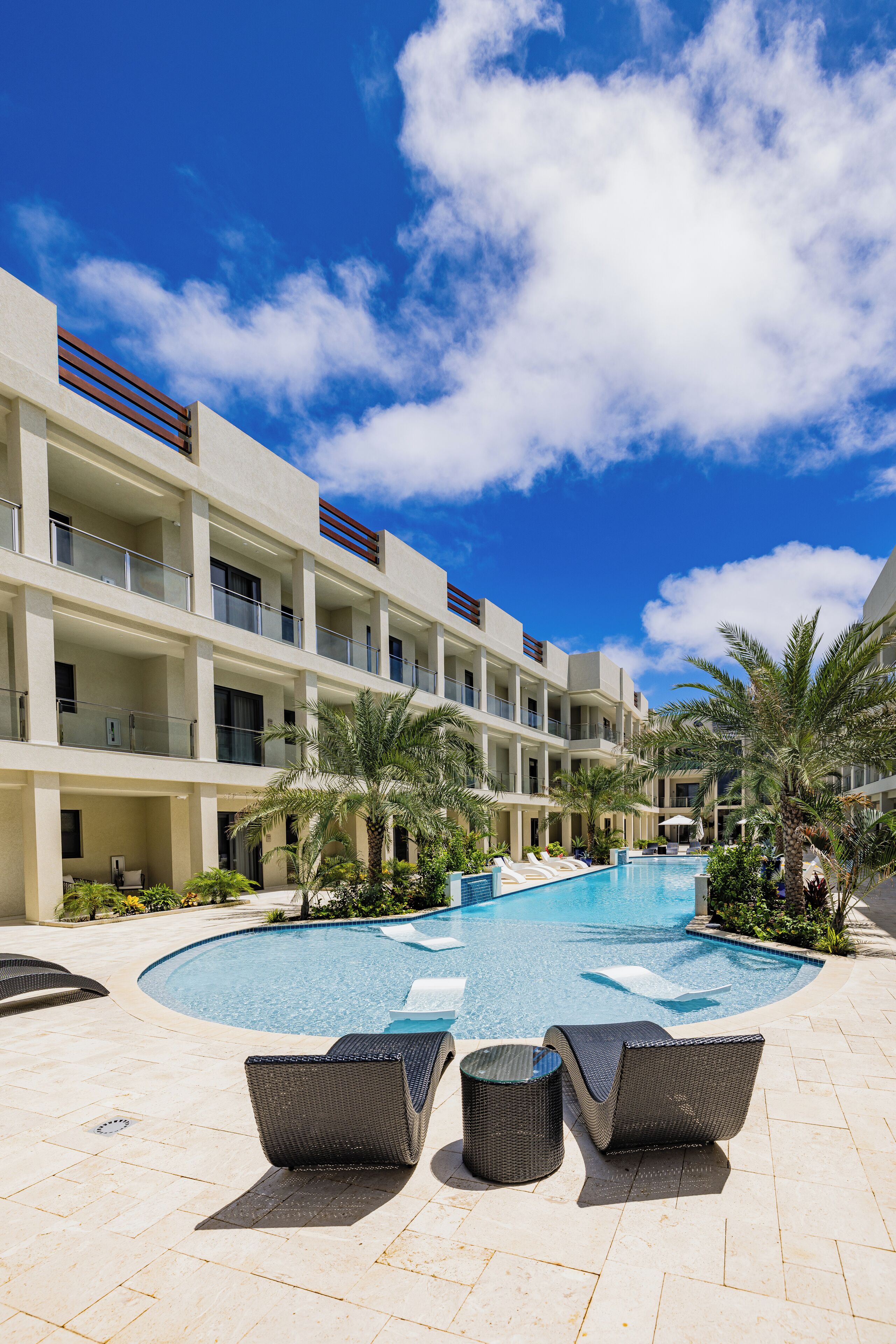 Un hotel con piscina, lettini e palme.