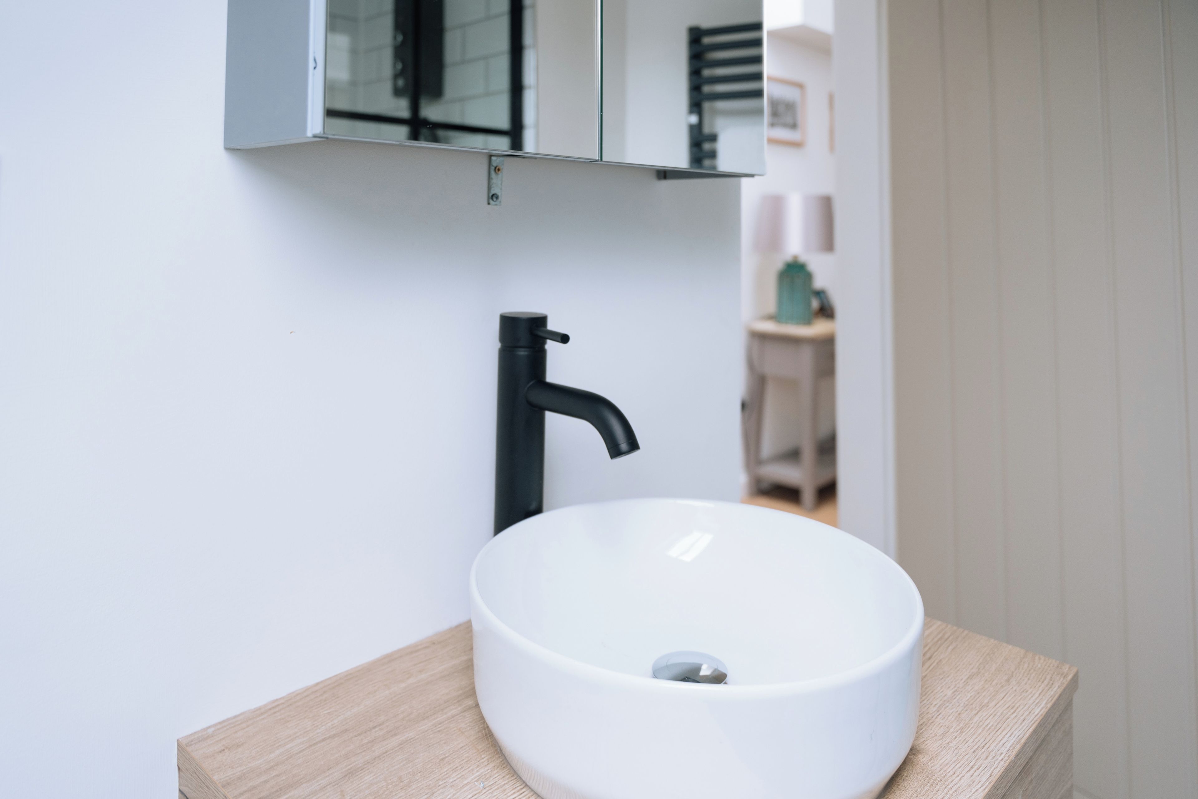 A bathroom with a white sink, black faucet, and a mirror above it.