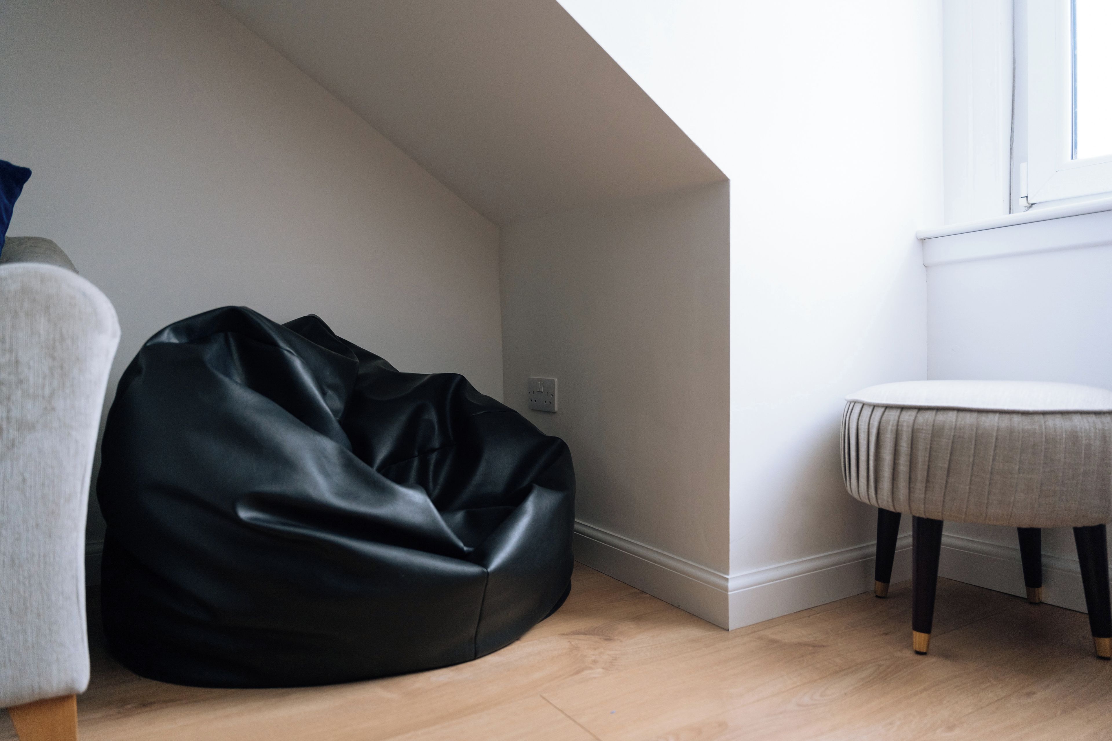 Una habitación con un sillón de cuero negro, una mesita redonda y una ventana que ofrece vistas al cielo.