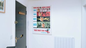 Une pièce avec une porte, un porte-manteau et une affiche au mur.