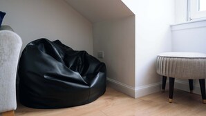 A room with a black bean bag chair, a round table with a light-colored top, and a window with white trim. - Charming Flat in the Heart of Edinburgh Old Town (Edinburgh)