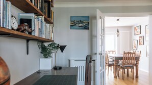 Ein Zimmer mit einem Holztisch, einer Pflanze, einem Heizkörper und einem Essbereich mit Stühlen und Tisch.