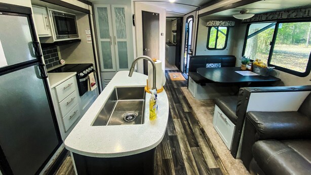Une cuisine compacte pour camping-car, équipée d’un évier, d’une cuisinière et d’un four à micro-ondes.