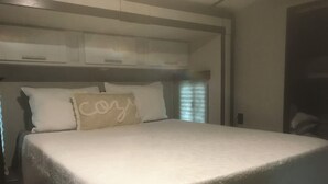 Un lit bien fait, avec un oreiller orné du mot « coquette ».