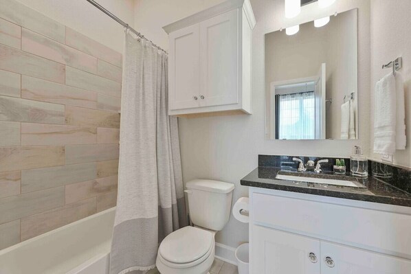 A bathroom with a shower, toilet, sink, and cabinets. - Ol’ Army Escape - Beautiful & Spacious Retreat in Aggieland! (College Station)