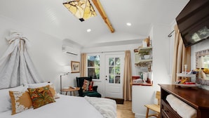 A bedroom with a bed, a chair, a desk, and a TV.