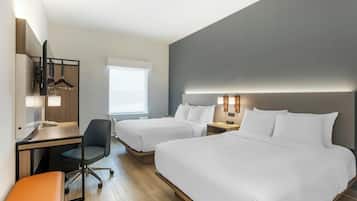 A hotel room with two beds, a desk, a chair, and a mirror.
