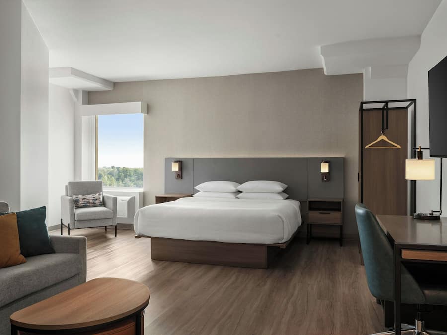 Una habitación de hotel moderna con cama, escritorio, silla, sofá y televisión.