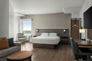 Una habitación de hotel moderna con cama, escritorio, silla, sofá y televisión.