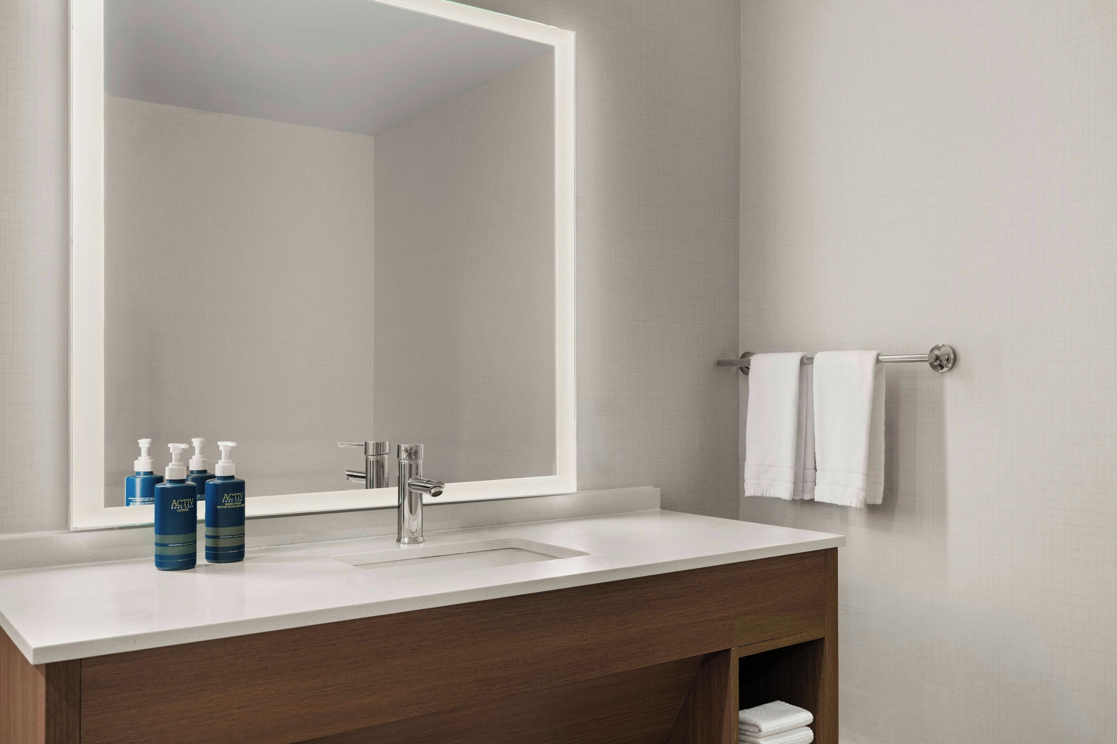 A bathroom with a white sink, a mirror, and a towel rack.