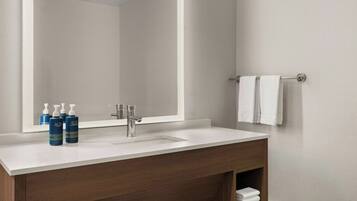 A bathroom with a white sink, a mirror, and a towel rack.