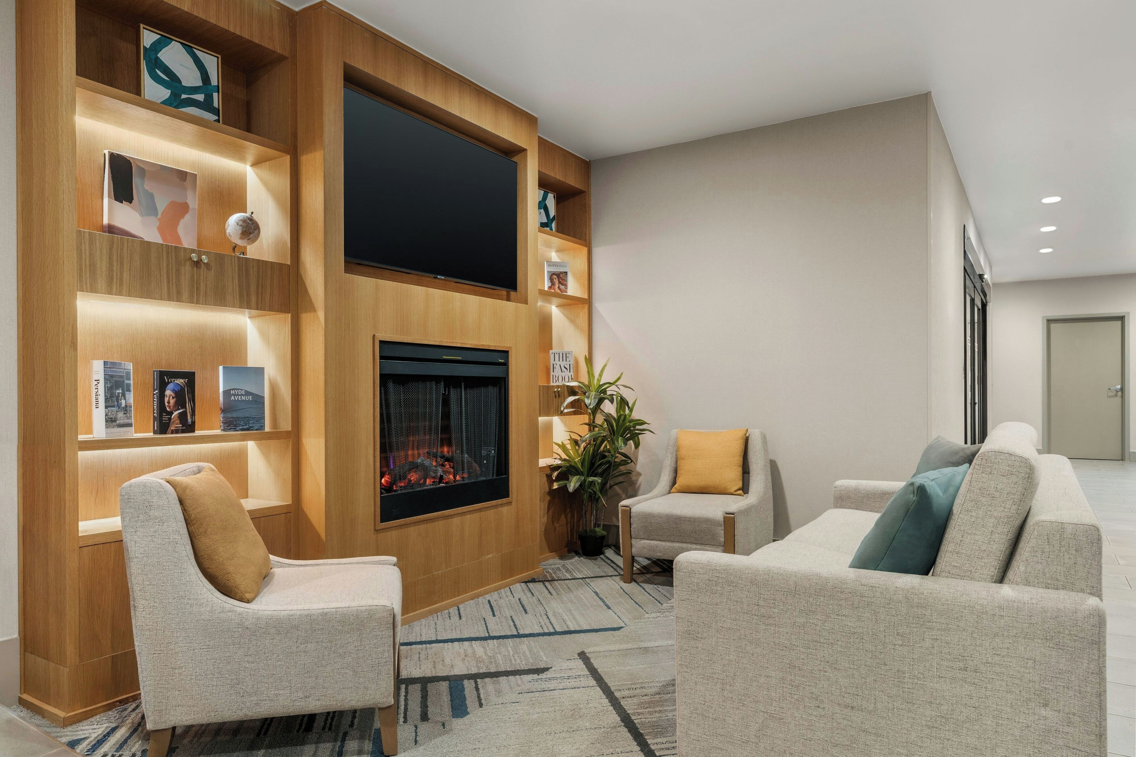 A modern living room with a fireplace, comfortable seating, and a flat-screen TV.