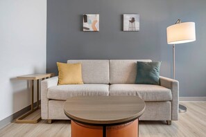 Ein modernes Wohnzimmer mit einer Couch, einem runden Tisch und einer Stehlampe.